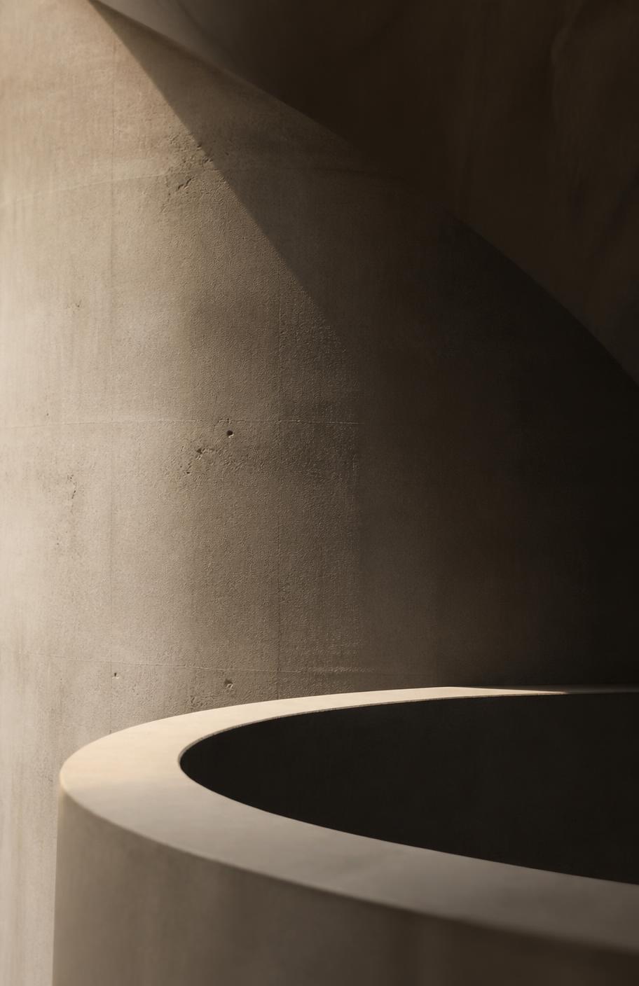 Curved concrete wall with raking light